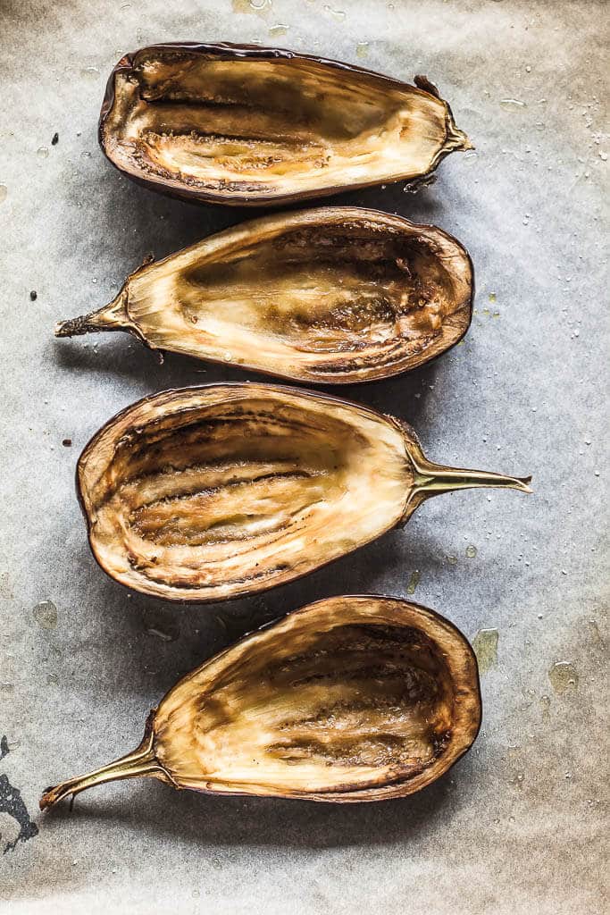 Hollowed out eggplants are spread on baking paper.