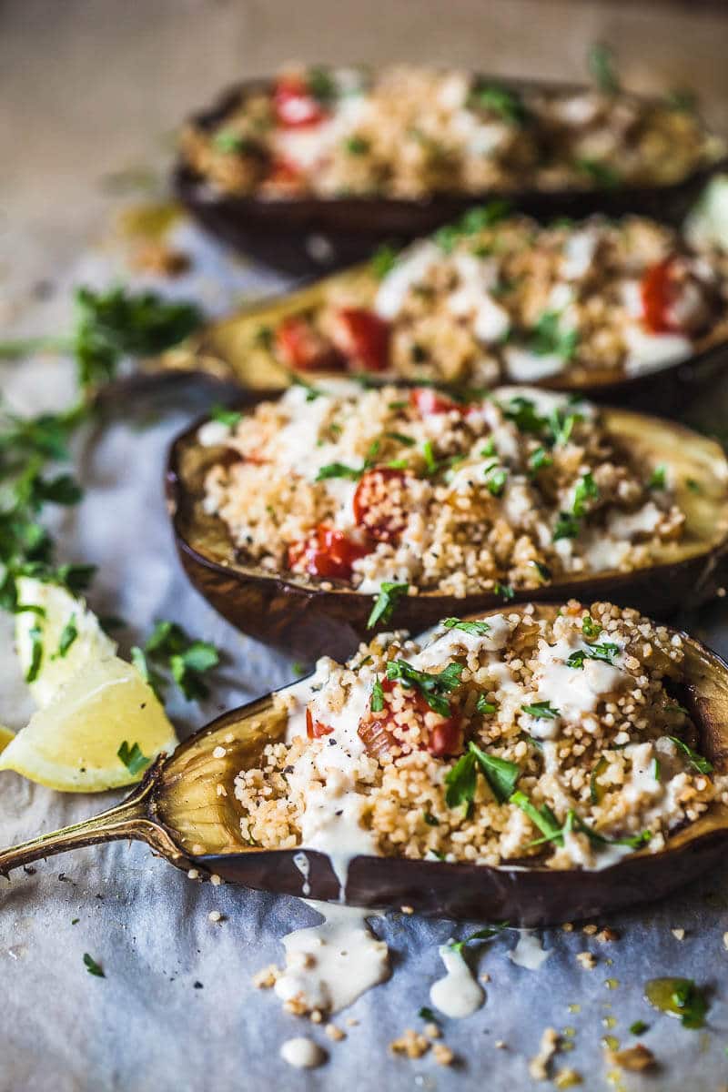 A side picture of Couscous Stuffed Eggplants topped with a fresh Lemon Tahini Sauce.