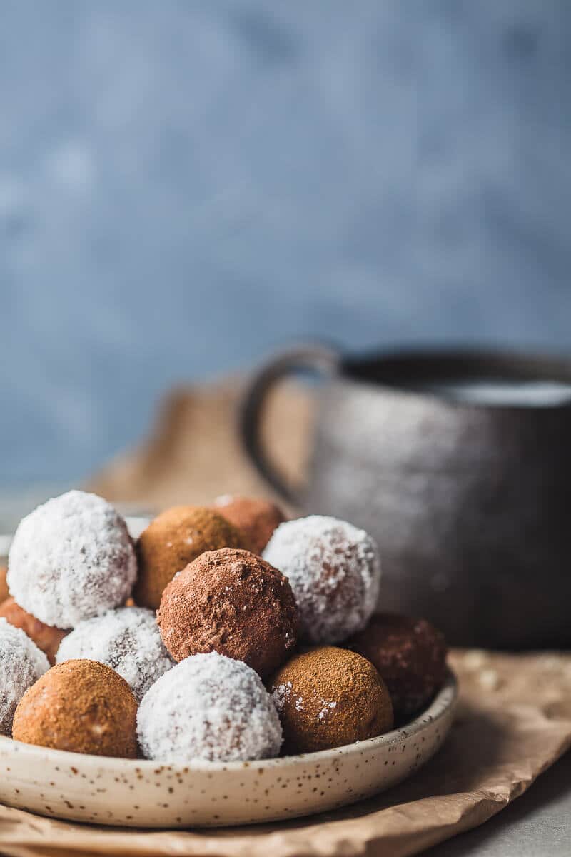 Almond pulp energy bites are arranged on a plate. A cup of almond milk is visible in the background.