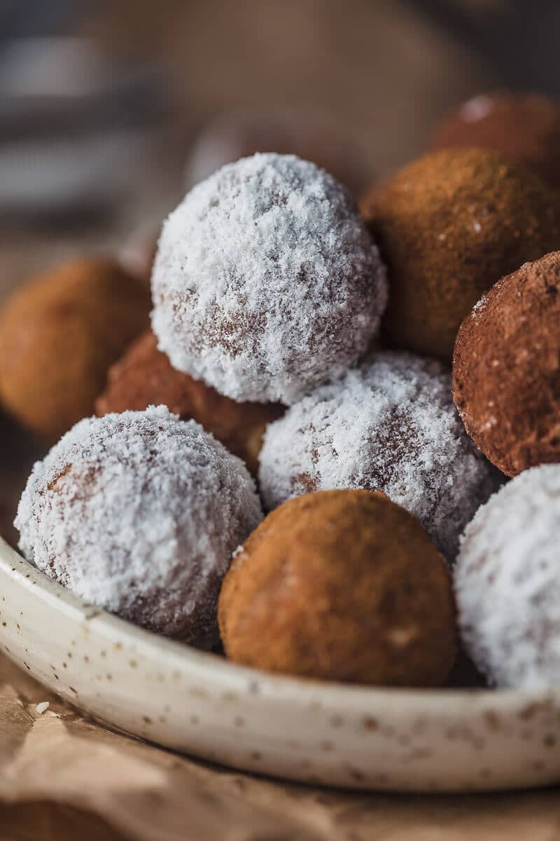 A close up picture of almond pulp energy bites. The bites are ball shaped and come in white and brown color.