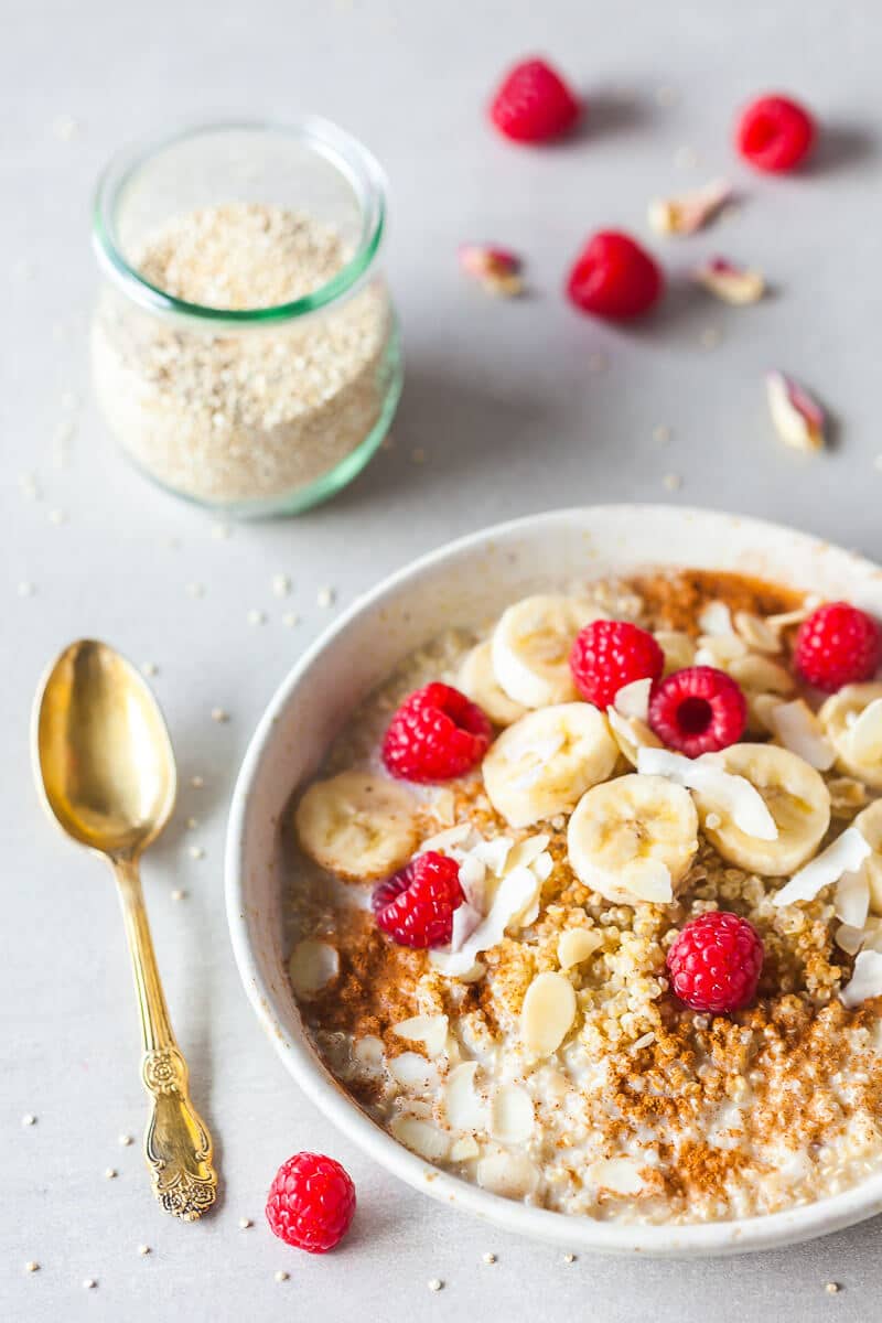 A vegan quinoa bowl, topped with banana slices and raspberries.